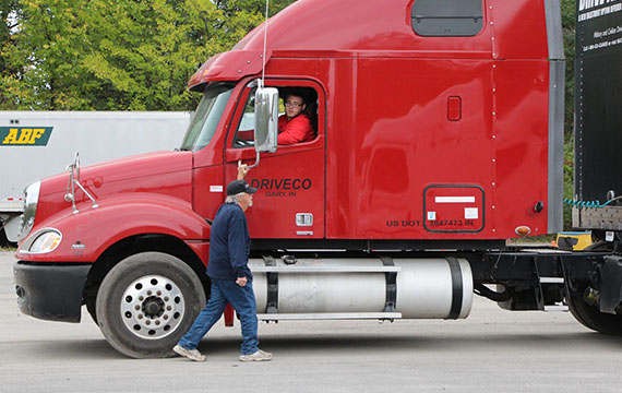 image of truck driver trainer helping student drive truck