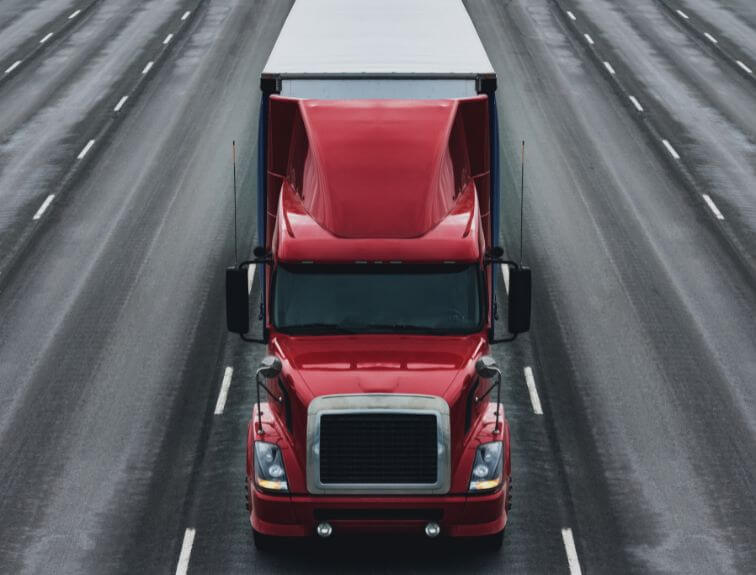 Image of a red and white semi driving on a multi-lane highway