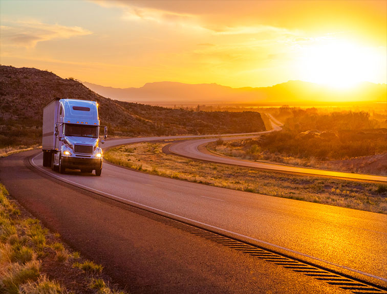 image of White truck on road with sunset in background