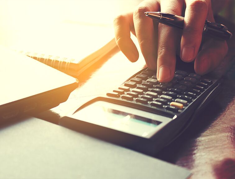 image of hand holding a pen typing on a calculator