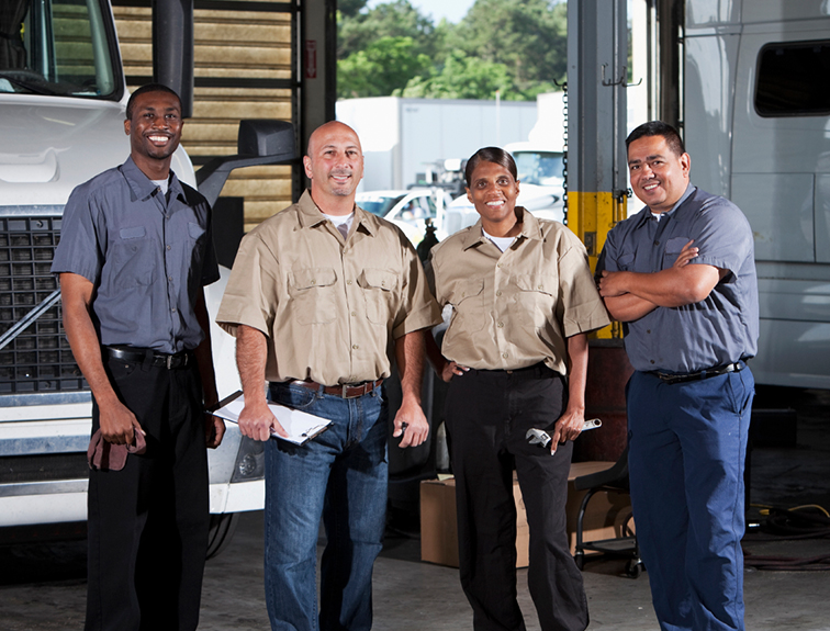 4 shop workers standing in front of a truck