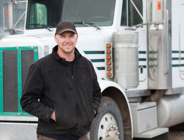 Image of trucker with hands inside pockets standing in front of white semi truck