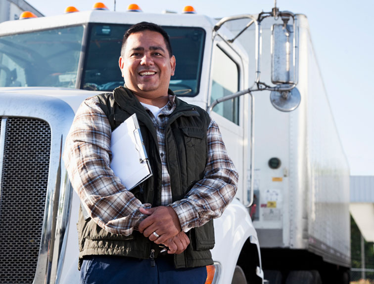 Truck driver standing in front of truck holding a clip board
