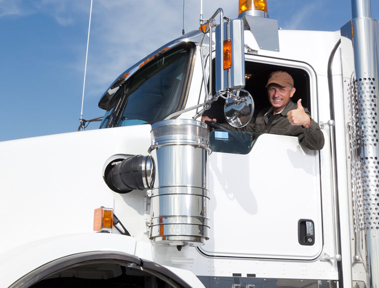 Truck driver with arm out the window of a white rig giving a thumbs up and smiling.