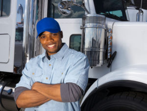 Truck driver with arms crossed leaning up against rig