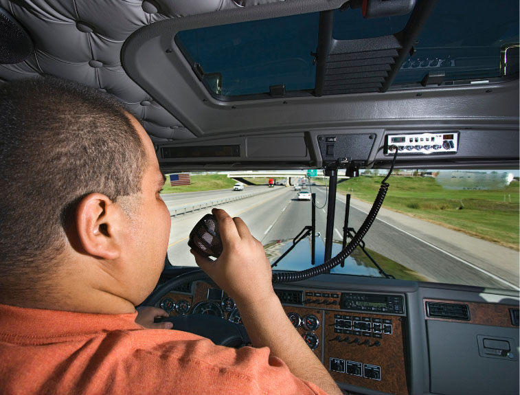 Man in the driver seat of a semi, talking on an intercom