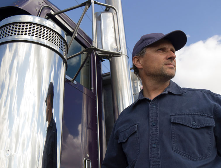 image of truck driver next to rig staring off into distance