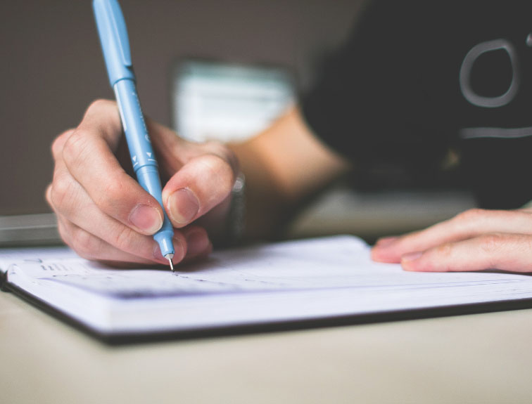 image of hands writing in notebook